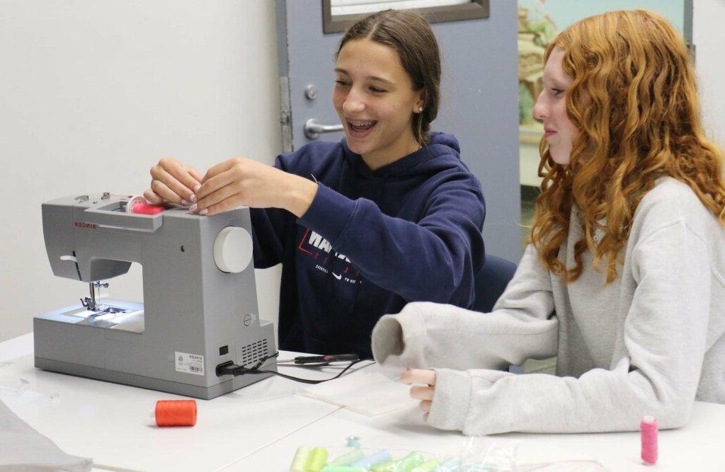 Girls with sewing machine laughing